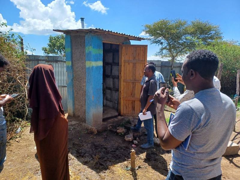 Visitors inspecting a finished toilet with a household member