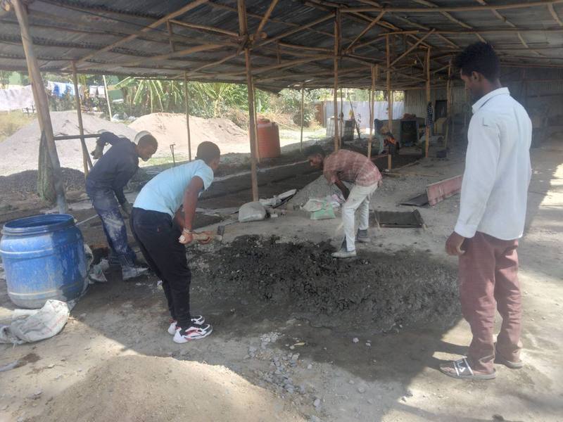 Workers mixing concrete at a small production yard